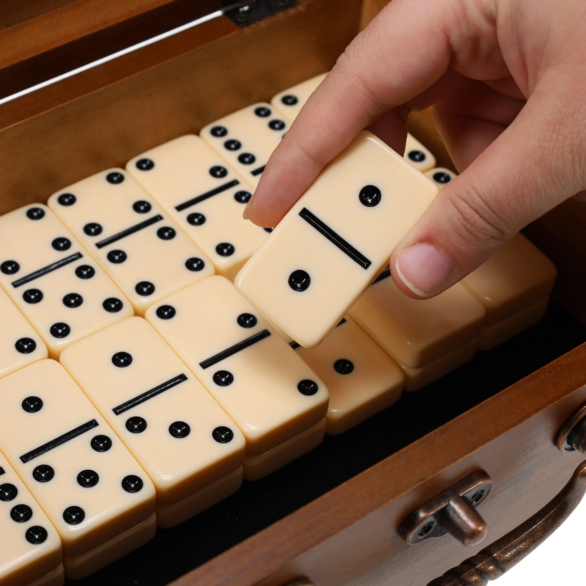 Close-up of thick ivory double-six dominoes with black pips in the wooden storage box