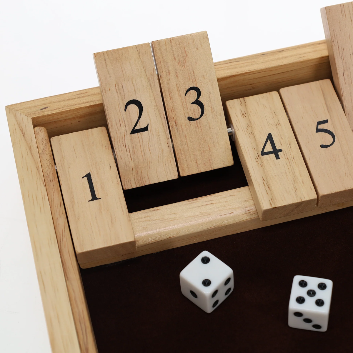 Close-up of wooden Shut the Box game with numbered flip tiles and dice on a felt playing surface