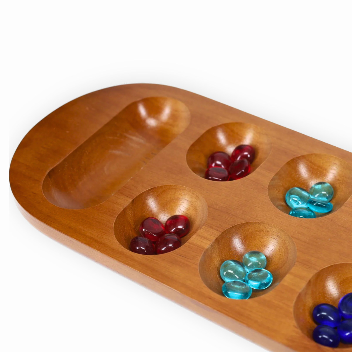 Close-up of wooden Mancala board with colorful glass stones in carved playing wells